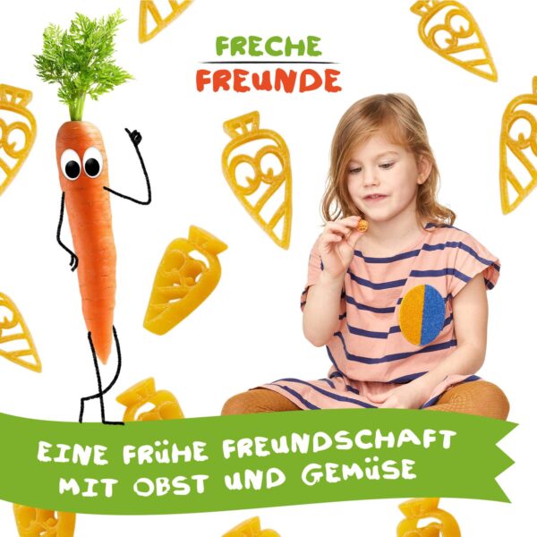 Freche Freunde Bio Gemüsenudeln Karotte – ein kleines Mädchen hält fröhlich eine Nudel in Möhrenform in der Hand, umgeben von frechen, karottenförmigen Nudeln und Karl Karotte mit Kulleraugen. Text: „Eine frühe Freundschaft mit Obst und Gemüse“.