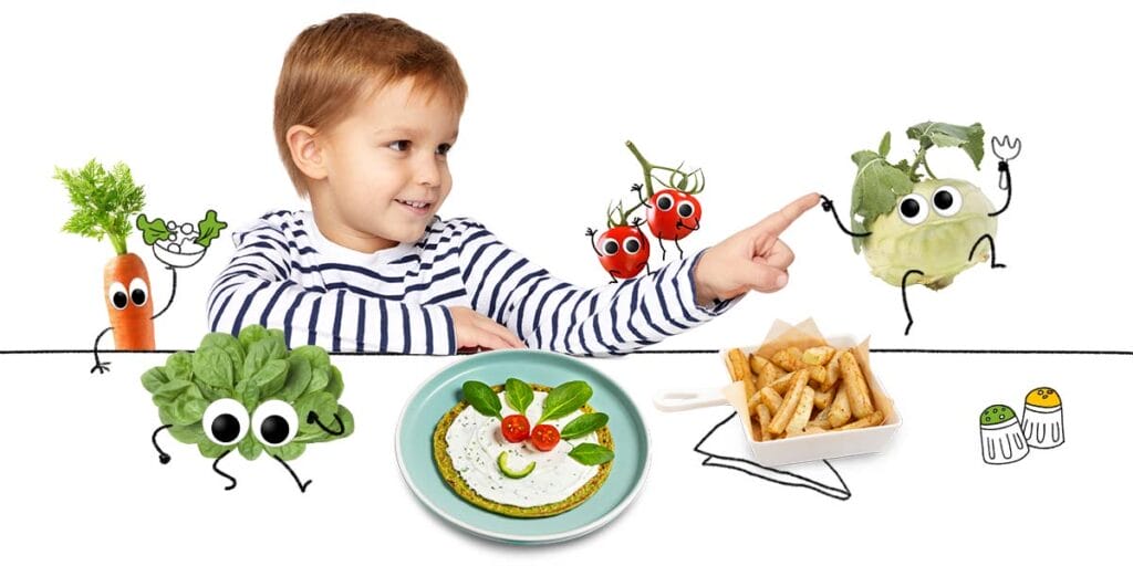Freche Freunde - Mehr Gemüse für Kinder - Banner: Junge hat Spaß am Tisch mit gemüsigen Freche-Freunde-Charakteren und vor ihm ein lustiges Spinat-Pfannkuchen-Gesicht