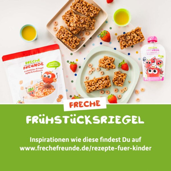 Aus Freche Freunde Bio Frühstücks-Kringeln Apfel & Erdbeere selbstgemachte Müsliriegel auf buntem Teller, mit frischen Erdbeeren und Saft. Links die Originalverpackung, rechts ein Freche Freunde Quetschie. Der Text lädt ein, weitere Rezepte unter frechefreunde.de zu entdecken