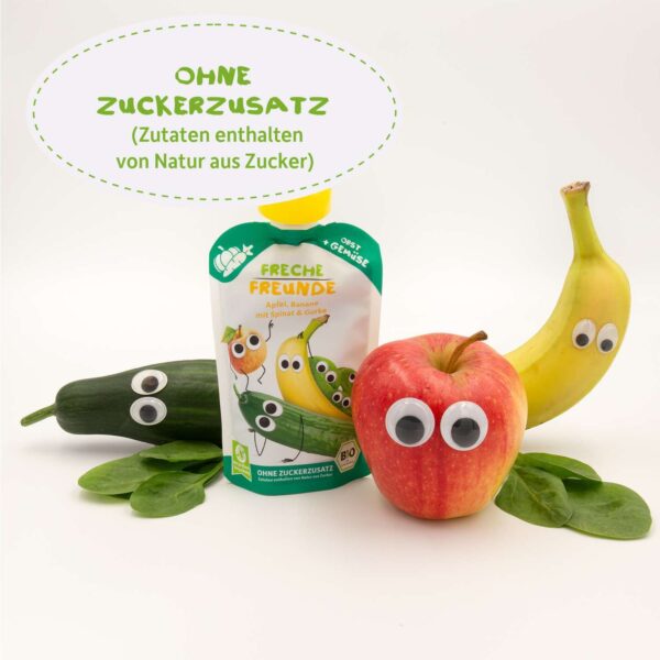 Freche Freunde Bio-Quetschie Apfel, Banane mit Spinat & Gurke umgeben von den fröhlichen Zutaten mit Wackelaugen. Text: „Ohne Zuckerzusatz – Zutaten enthalten von Natur aus Zucker“. Perfekt für gesunde Zwischenmahlzeiten.