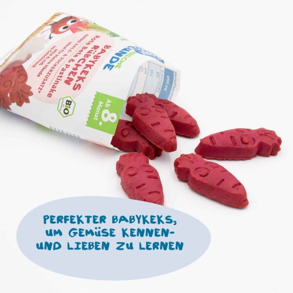 Eine aufgerissene Tüte der Freche Freunde Babykekse liegt auf einer weißen Fläche, aus der die kleinen roten Rübchenkekse herauspurzeln. Die liebevoll geprägten Keksfiguren zeigen kleine Gesichter. Daneben steht: „Perfekter Babykeks, um Gemüse kennen- und lieben zu lernen“.