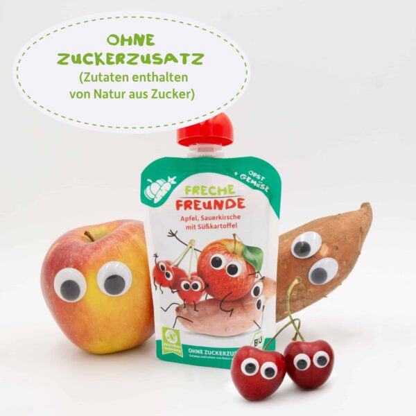 Der Bio-Quetschie „Apfel, Sauerkirsche mit Süßkartoffel“ steht im Mittelpunkt, flankiert von einem Apfel, zwei Kirschen und einer Süßkartoffel mit witzigen Augen. Text: „Ohne Zuckerzusatz – Zutaten enthalten von Natur aus Zucker“.