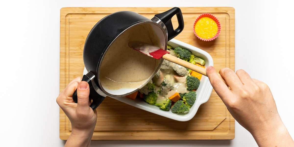 Soße über das Gemüse für den Brokkoliauflauf vegan mit Süßkartoffeln.
