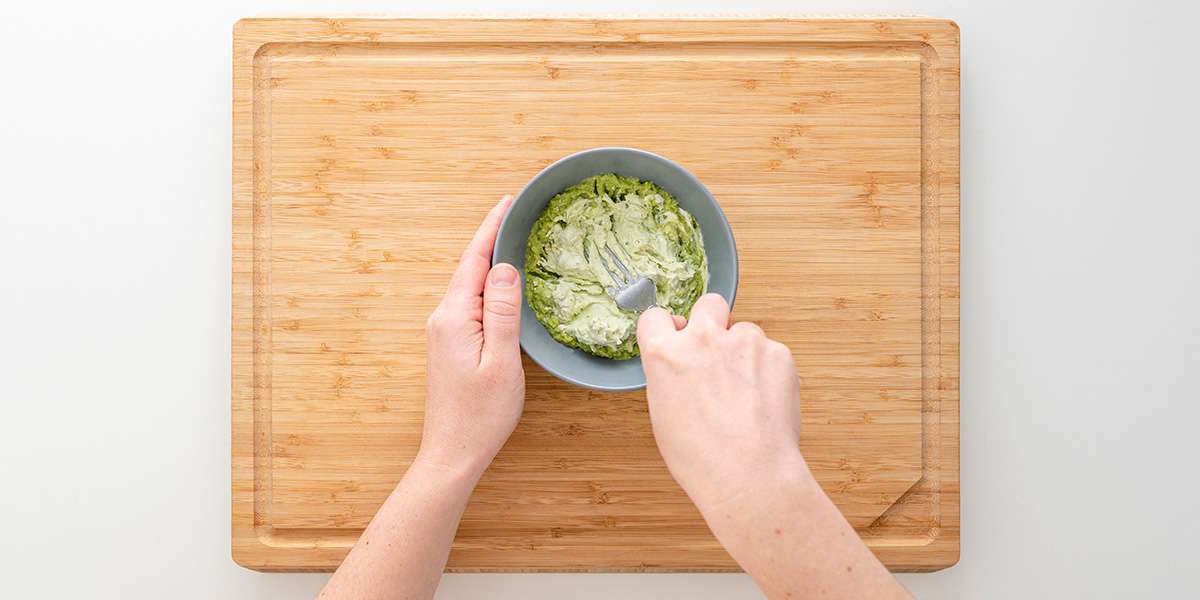 Avocado wird mit Gabel in einer Schüssel gequetscht für das Gemüse-Sandwich.