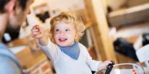 Freche Freunde - Blogbeitrag 10 Tipps fürs Kochen mit Kindern - Kind bietet Papa mit Strahlen etwas vom Essen an