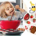 Kuchen für Kinder backen macht Spaß! Das Mädchen schleckt den Teig vom Löffel ab und Edda Erdbeere hat den Teig am ganzen Körper.