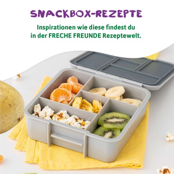 Snackbox-Rezepte: Brotdose gefüllt mit Mandarinen, Kiwi, Bananen, Popcorn darüber steht: Inspirationen wie diese findest du in der Freche Freunde Rezeptwelt.