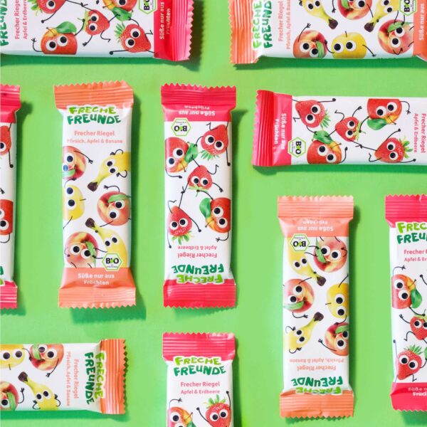 Flach gelegte Freche Freunde Riegel verschiedener Sorten, unter anderem Pfirsich-Apfel-Banane mit den Charakteren Peggy Pfirsich, Alfred Apfel und Bob Banane auf der Verpackung.