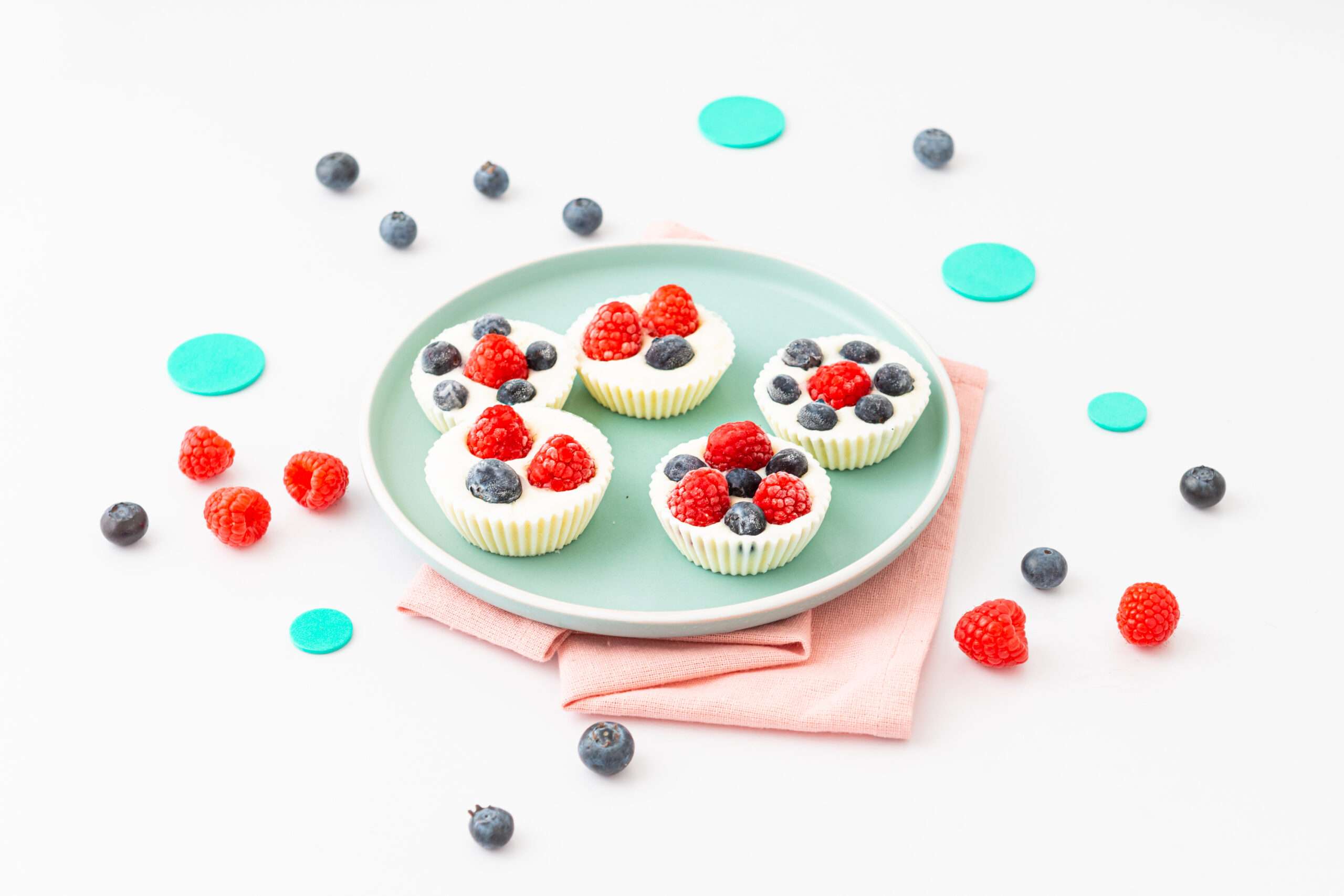 Frozen Joghurt Törtchen auf einem Teller serviert mit Heidelbeeren und Himbeeren