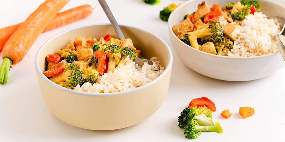 Hähnchen Curry mit Gemüse und Reis in Schüsseln serviert.